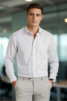 Young man in a white striped shirt and beige pants standing confidently in a modern office setting.