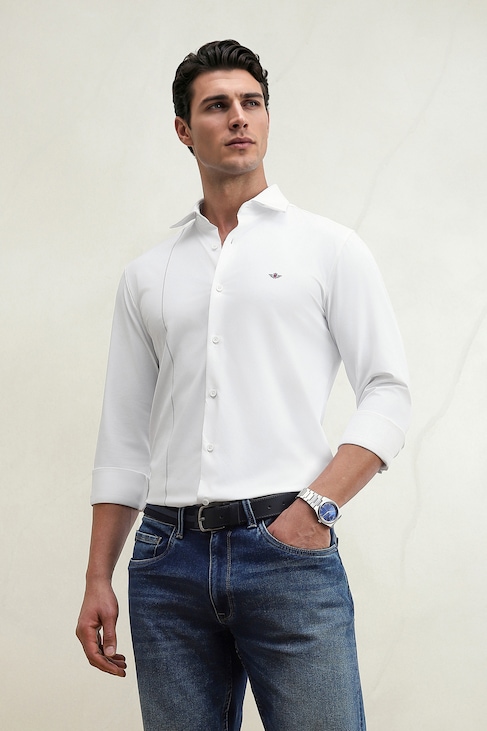 Man modeling a white button-down shirt, jeans, black belt, and wristwatch against a light background.