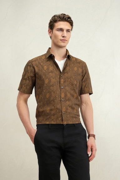 Young man modeling a brown patterned short-sleeve shirt, white undershirt, black trousers, and wristwatch against a plain background.